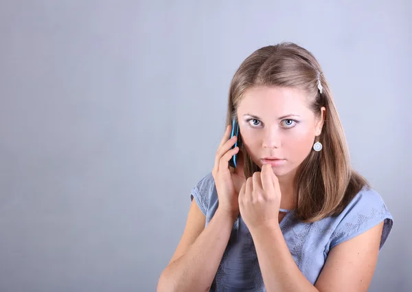 Menina bonita em uma camisa azul falando no telefone — Fotografia de Stock