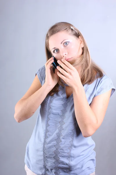 Beautiful girl in a blue shirt talking on the phone — Stock Photo, Image