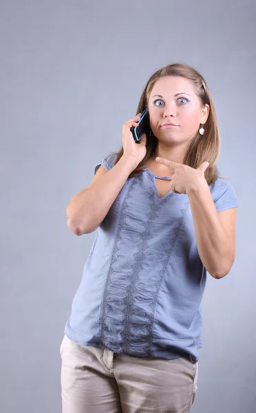 Menina bonita em uma camisa azul falando no telefone — Fotografia de Stock