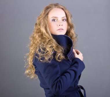 Durgun bir manzara mavi ceket gri arka plan üzerine ile güzel kıvırcık sarışın