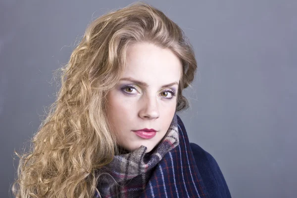 Beautiful curly blonde with a languid sight in the blue coat on gray background — Stock Photo, Image