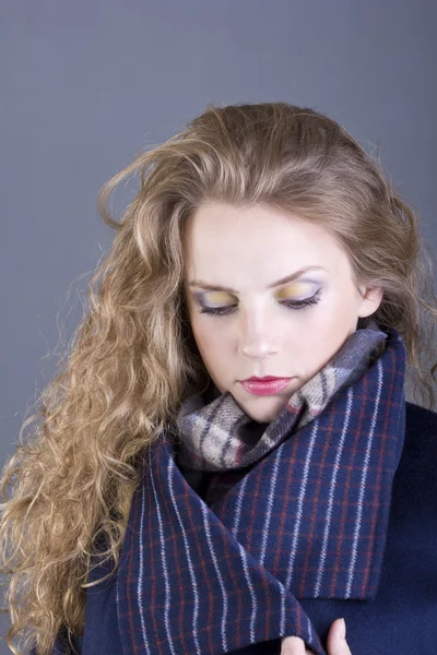 Hermosa rubia rizada con una vista lánguida en el abrigo azul sobre fondo gris — Foto de Stock