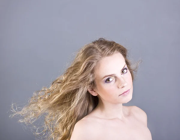Piękna blondynka długie kręcone włosy i brązowe oczy na szarym tle — Zdjęcie stockowe