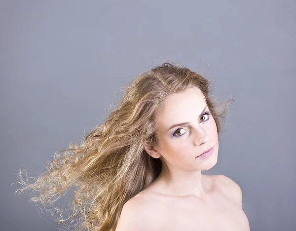 The beautiful blonde with long curly hair and brown eyes on a gray background — Stock Photo, Image