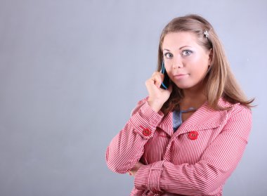 mavi gözlü güzel genç kız tarafından cep telefonu gri bir arka plan üzerinde konuşuyor.