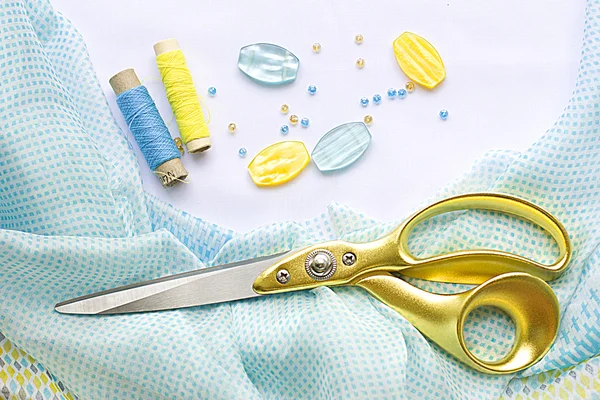 Velké nůžky s úchyty pro zlatou ležet na krásné hedvábné šaty žluto modré — Stock fotografie