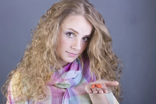 Schönes Mädchen mit weißem lockigem Haar, das Pillen auf grauem Hintergrund hält — Stockfoto