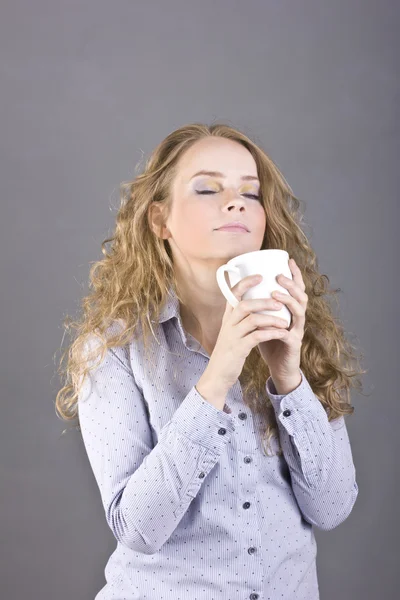 Güzel sarışın kıvırcık saçlı beyaz bir kupa kahve veya çay içme — Stok fotoğraf