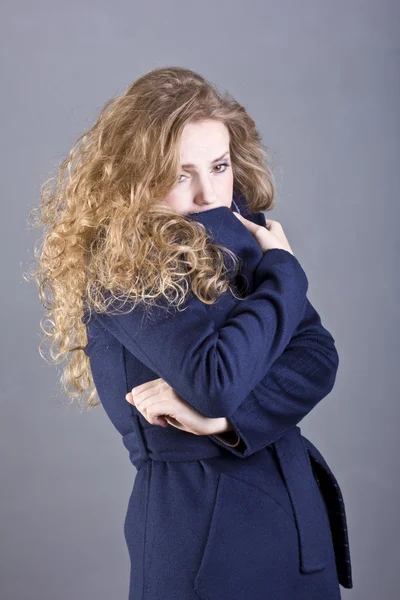 Charming blonde in a blue coat on gray background — Stock Photo, Image