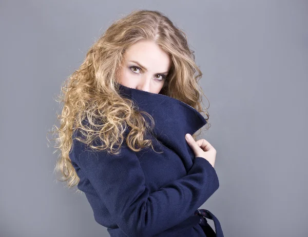 Charmante Blondine in blauem Mantel auf grauem Hintergrund — Stockfoto