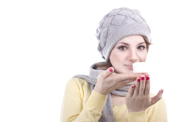 Hermosa joven sosteniendo un pequeño frasco blanco con crema sobre un fondo blanco — Foto de Stock