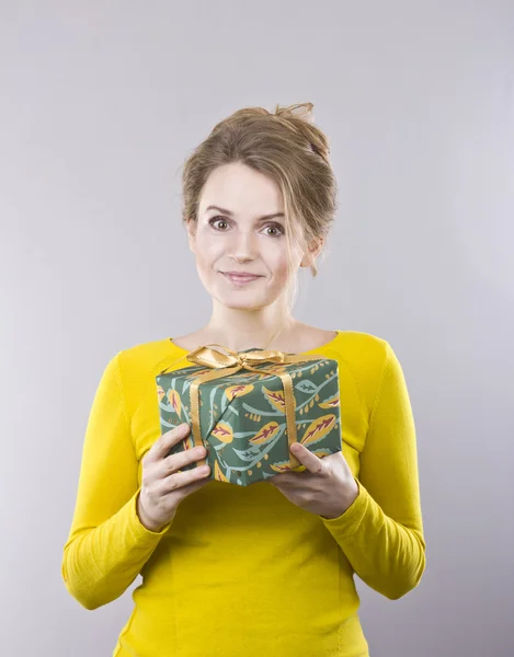 Beautiful young woman holding a bright gifts on gray background — Stock Photo, Image