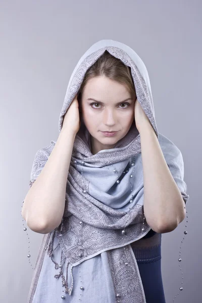 Adorável jovem loira em um cachecol azul pálido em sua cabeça no fundo cinza — Fotografia de Stock