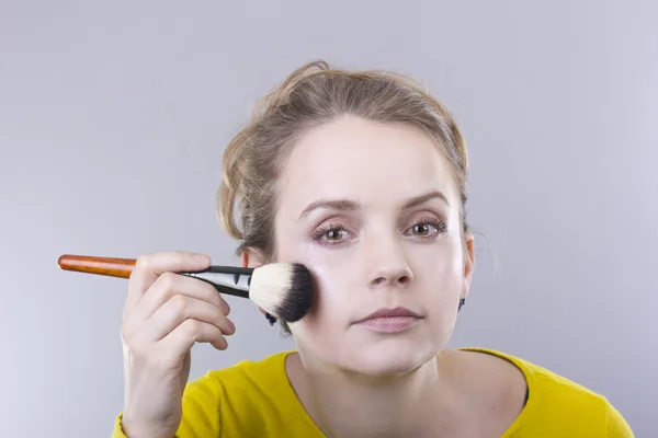 Junge schöne Blondine in leuchtend gelber Morgenjacke schüttet Puder ins Gesicht — Stockfoto