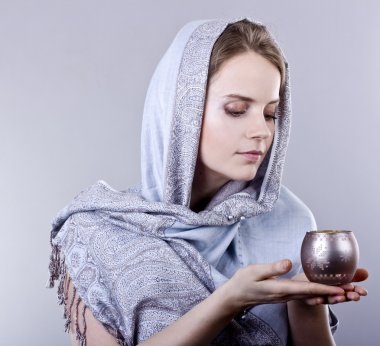 güzel bir genç kadın gri arka plan üzerine güzel bir mum tutan mavi atkı sarılı