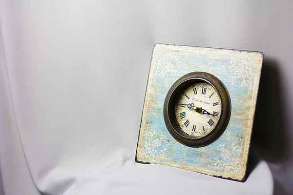 Blauwe klok in de stijl van provence op de grijze stof. vintage horloges. gele kaars — Stockfoto