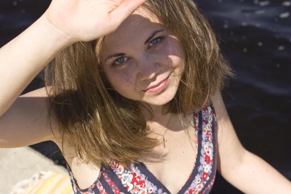 Beautiful young woman basking in the sun near the water — Stock Photo, Image