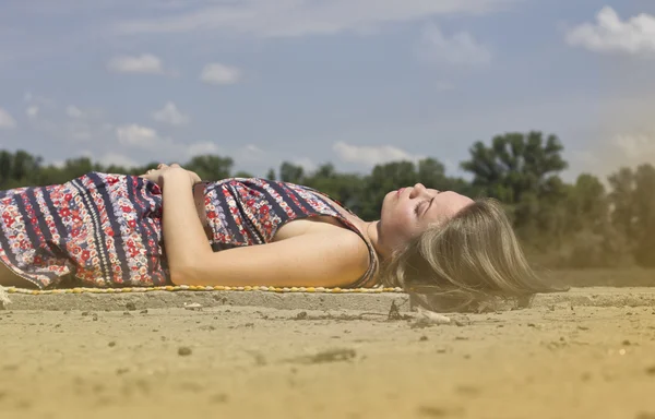 Beautiful young woman basking in the sun near the water — Stock Photo, Image