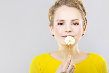 güzel sarışın gri bir arka plan üzerinde elinde bir çiçek