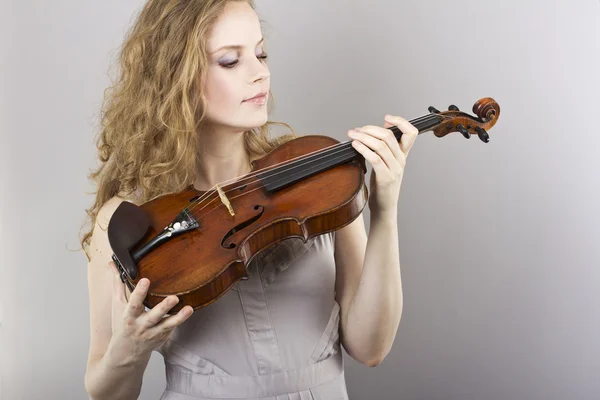 Vackra lockiga blondin i grå klänning med röda violin i hennes händer — Stockfoto