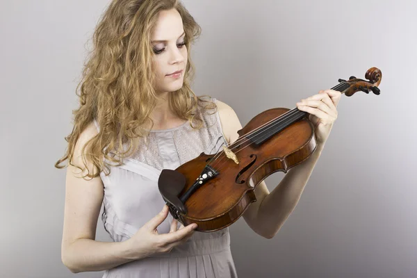 Belle blonde bouclée en robe de soirée grise avec violon rouge dans les mains — Photo