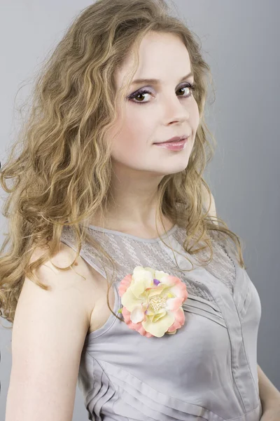 Beautiful curly blonde in gray evening dress on a gray background — Stock Photo, Image