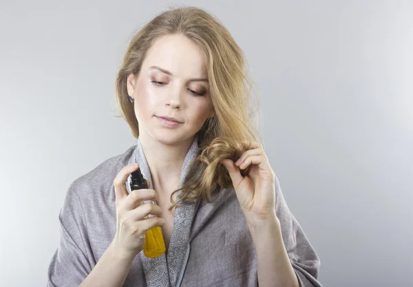 Beautiful curly blonde takes care of her hair. — Stock Photo, Image