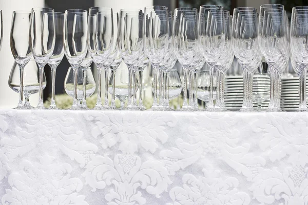 Wedding glasses on the white silk tablecloth, on the street. sunny weather. wedding preparations.