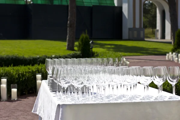 Wedding glasses on the white silk tablecloth, on the street. sunny weather. wedding preparations.