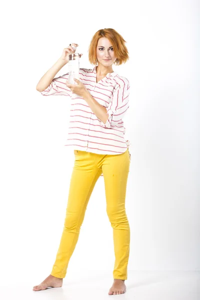 Beautiful young woman with short red hair drinking mineral water from a bottle. Portrait of a woman on a white background — Stock Photo, Image