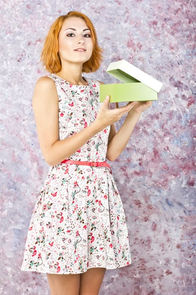 Charming young girl holding a gift box. Bright oil background. Hair style. Red short hair — Stock Photo, Image