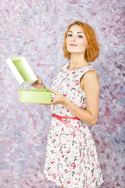 Charmig ung flicka håller en presentförpackning. ljusa olja bakgrund. frisyr. rött kort hår — Stockfoto