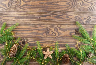 Kozalaklı dallar ve kahverengi arka planda bir yıldız. Noel ve Yeni Yıl konsepti. Yatay yönelim, kopyalama alanı, üst görünüm.