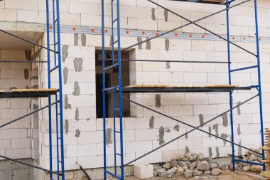 Beton bloklardan yapılmış bir evin arka planında iskele var..