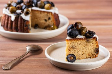 Kahverengi ahşap masada zeytinli ve limonlu bir dilim pasta..