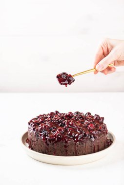 Siyah frenk üzümü reçelli Brownie ve hafif arka planda kaşıklı bir el..