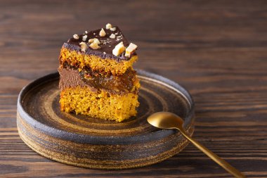 Kahverengi ahşap bir masada çikolatalı ve fındıklı bir parça balkabağı turtası. Şeker, glüten ve laktozsuz vejetaryen.