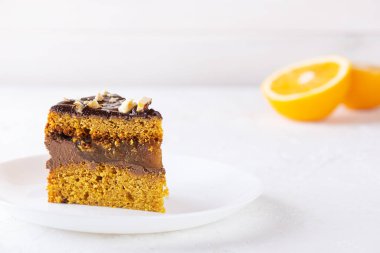 Beyaz tabakta çikolatalı, portakallı ve fındıklı vejetaryen kabak turtası. Şeker, glüten ve laktozsuz.