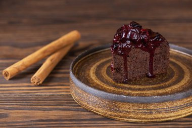 Kahverengi ahşap bir masada siyah üzümlü çikolatalı kek, patlıcan ve tarçın. Şeker, glüten, laktozsuz, vejetaryen.