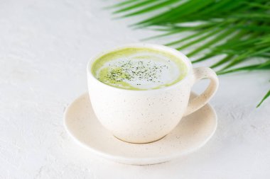 Hindistan cevizi sütü ve kenevir tohumlu kibrit latte çayı bir palmiye dalının arka planında..