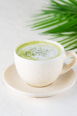 Palmiye dalının arka planında hindistan cevizi sütü ile kibrit latte çayı.