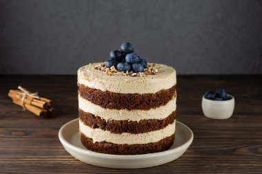 Tahta bir masada hindistan cevizi kremalı, cevizli ve baharatlı havuçlu kek. Şeker, glüten ve laktozsuz vejetaryen.