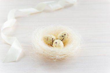 Tahta bir masanın üzerinde çikolata yumurtaları olan bir yuva. Paskalya konsepti.