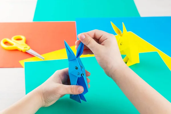 The process of creating a rabbit paper craft by a kid at the table.