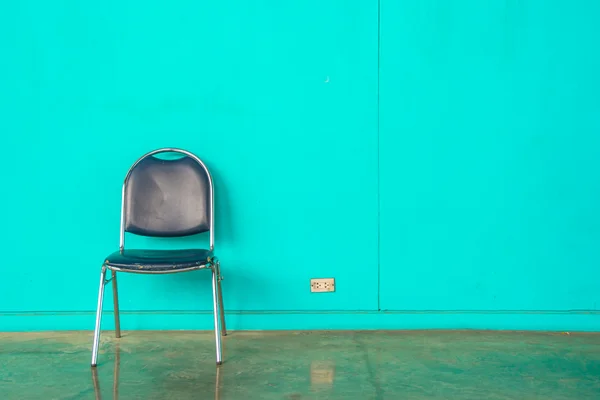 Krzesło na zielony ściana — Zdjęcie stockowe
