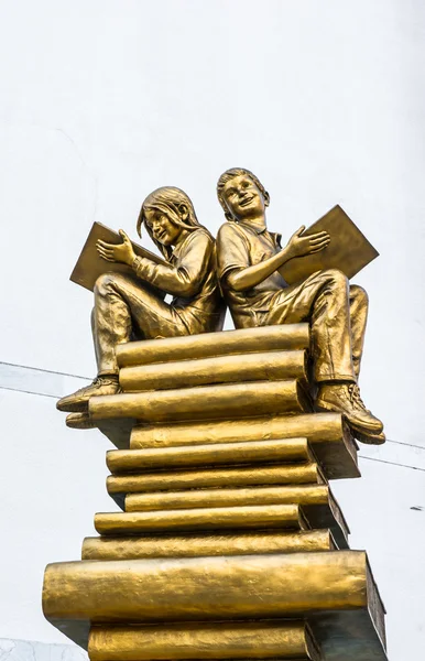 Estátua menino e menina sentado no livro — Fotografia de Stock