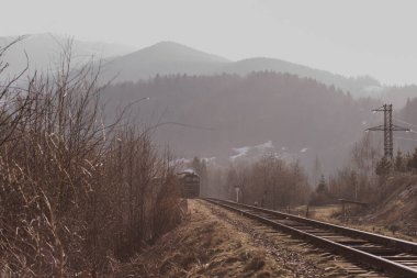Eski yolcu treni, Carpathian dağları arasında ilkbaharın başlarında gün batımında tren yolunda ilerliyor.