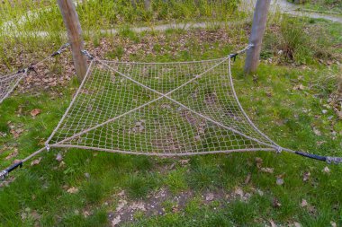 Çocukların tırmanma ağları, tahta direklerin arasından yere kadar uzanır. Metal bağlayıcıların güçlü halatlarından yapılmış üst görüntü ağı. Yazın çekilen fotoğraf.