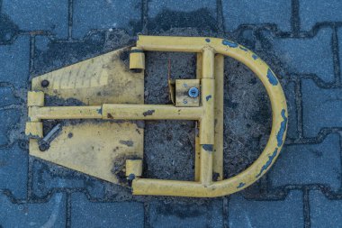 Sarı park engelleyici kaldırım taşlı yola vidalanmış. Toprağın etrafındaki park engelleyicinin kendisi yukarıdan çekilmiş.