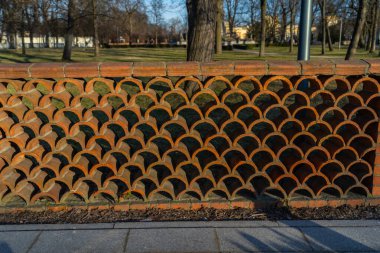 Doğal fayanslardan yapılmış çitler, yay şeklindeki fayanslardan birini güneşli havada çekilen diğer fotoğrafın üstüne yerleştirdi. Çit, Varşova Polonya 'daki Willianow Sarayı' na yerleştirildi.